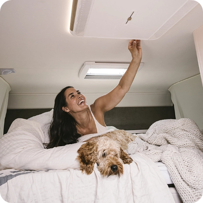Photo d'une dame dans un camping-car qui allume sa climatisation de toit